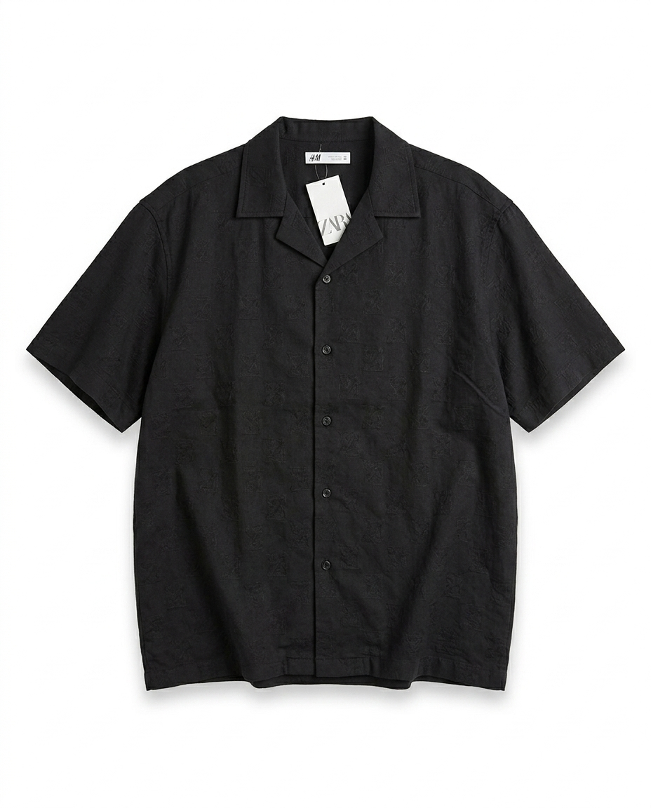IMG_5818 A sleek black short-sleeve shirt with subtle woven texture and a structured relaxed fit. Minimal, versatile, and elevated with quiet luxury energy.